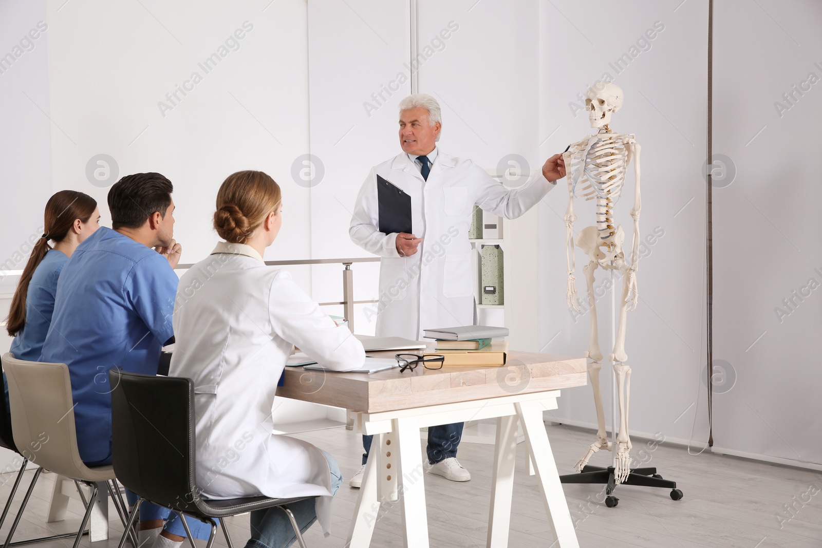 Photo of Medical students and professor studying human skeleton anatomy in classroom