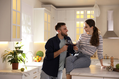 Photo of Lovely young couple drinking wine while cooking together in kitchen