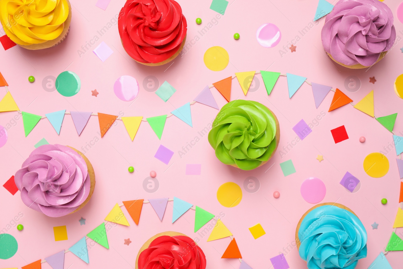 Photo of Colorful birthday cupcakes on light pink background, flat lay