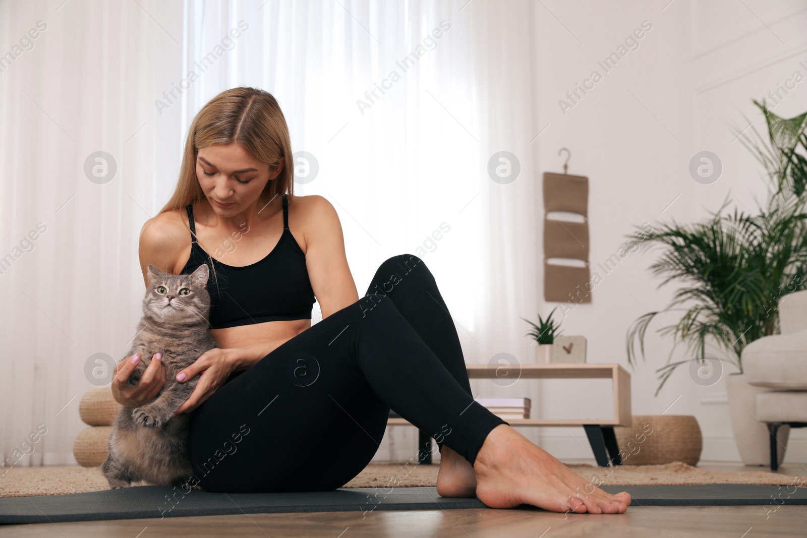 Photo of Woman stroking her cat while practicing yoga at home