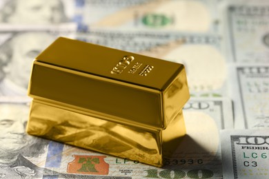 Photo of Shiny gold bars on dollar banknotes, closeup