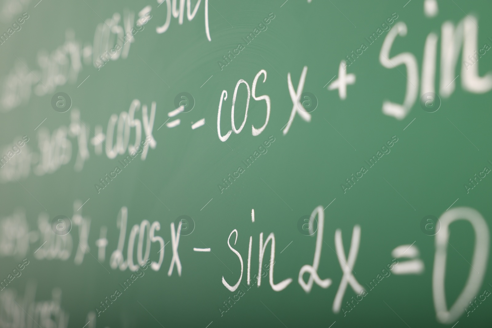 Photo of Many different math formulas written on green chalkboard, closeup