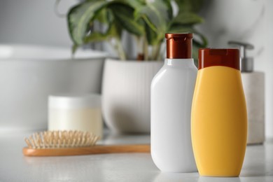 Photo of Shampoo, conditioner and hairbrush near sink on bathroom counter, space for text