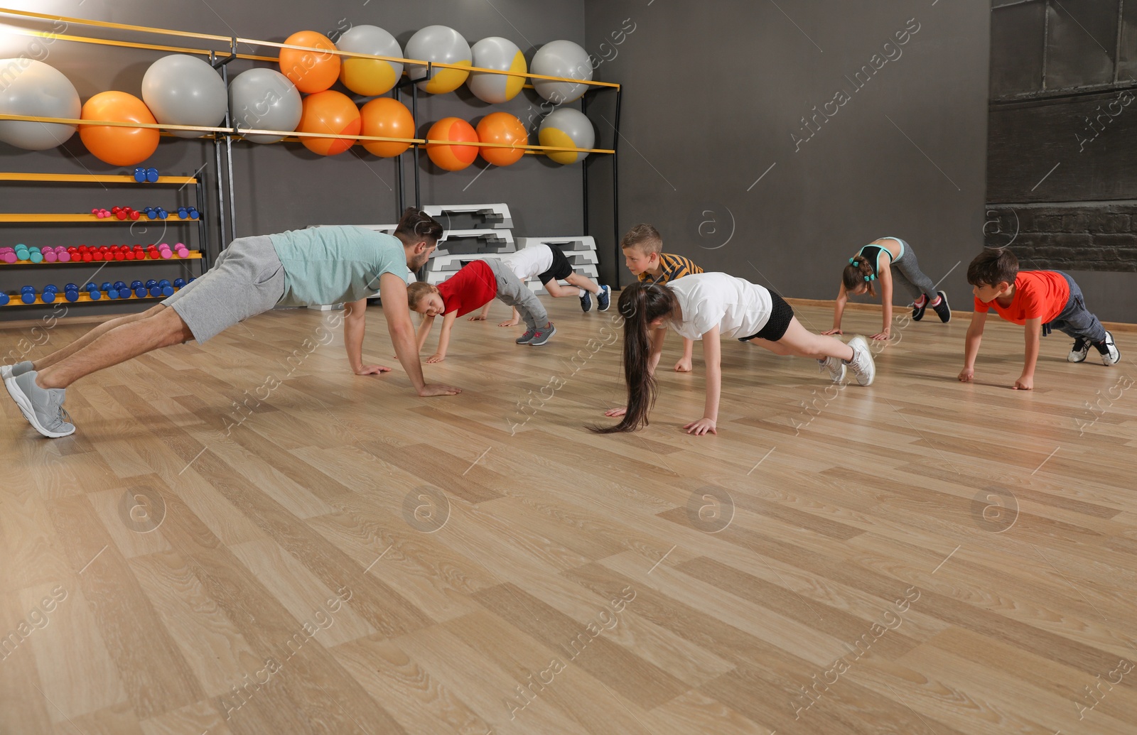 Photo of Cute little children and trainer doing physical exercise in school gym. Healthy lifestyle