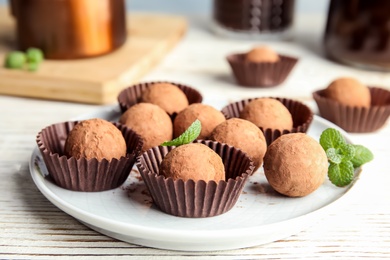 Plate with chocolate truffles on wooden table