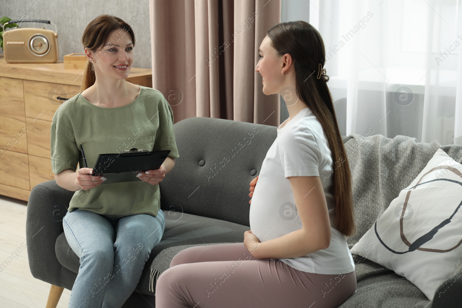 Photo of Doula working with pregnant woman on sofa at home. Preparation for child birth