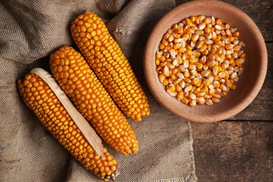 Photo of Delicious ripe corn cobs and bowl with seeds on wooden table, flat lay