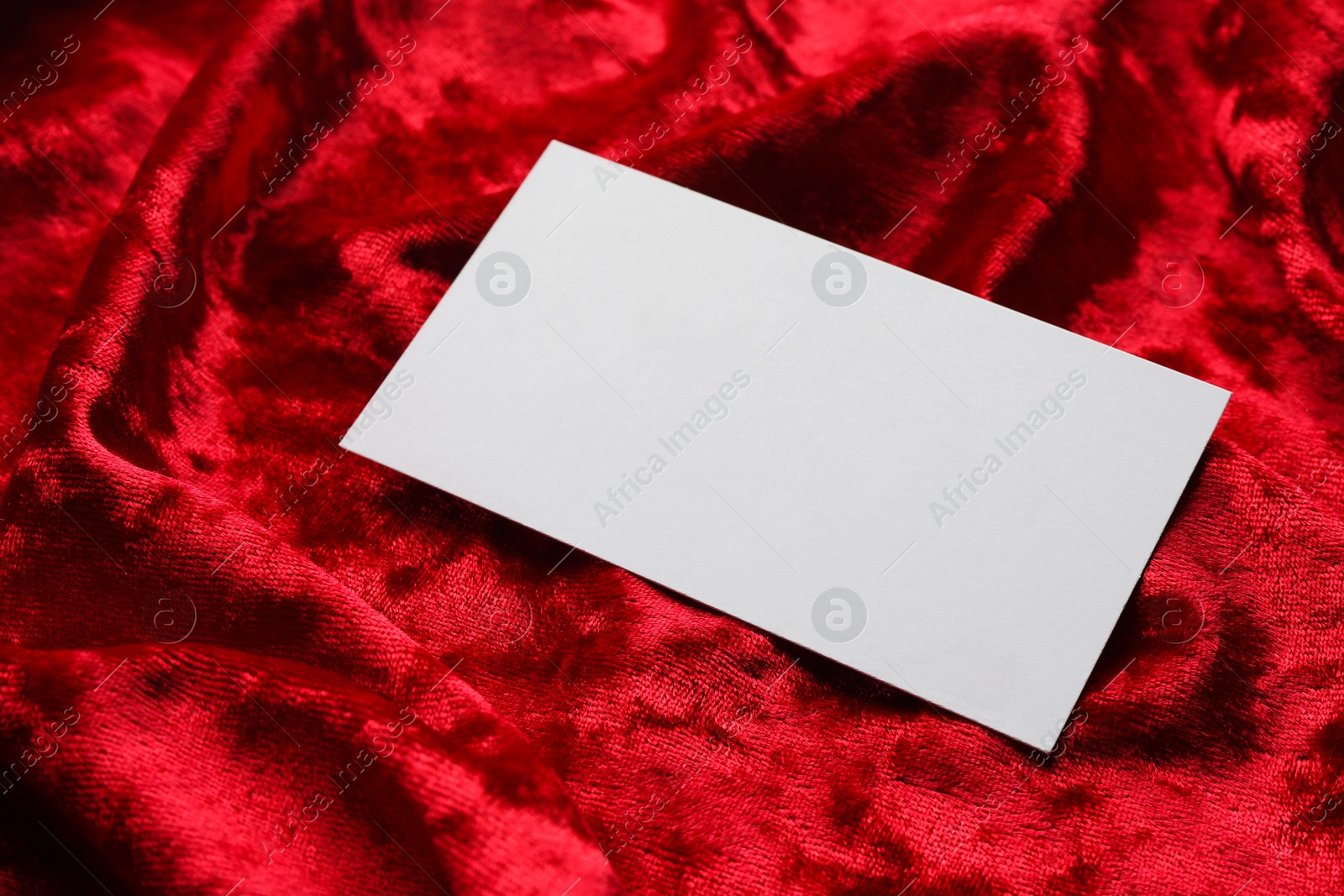 Photo of Blank business card on red fabric, closeup. Mockup for design