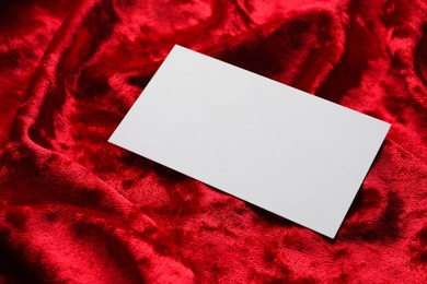 Photo of Blank business card on red fabric, closeup. Mockup for design