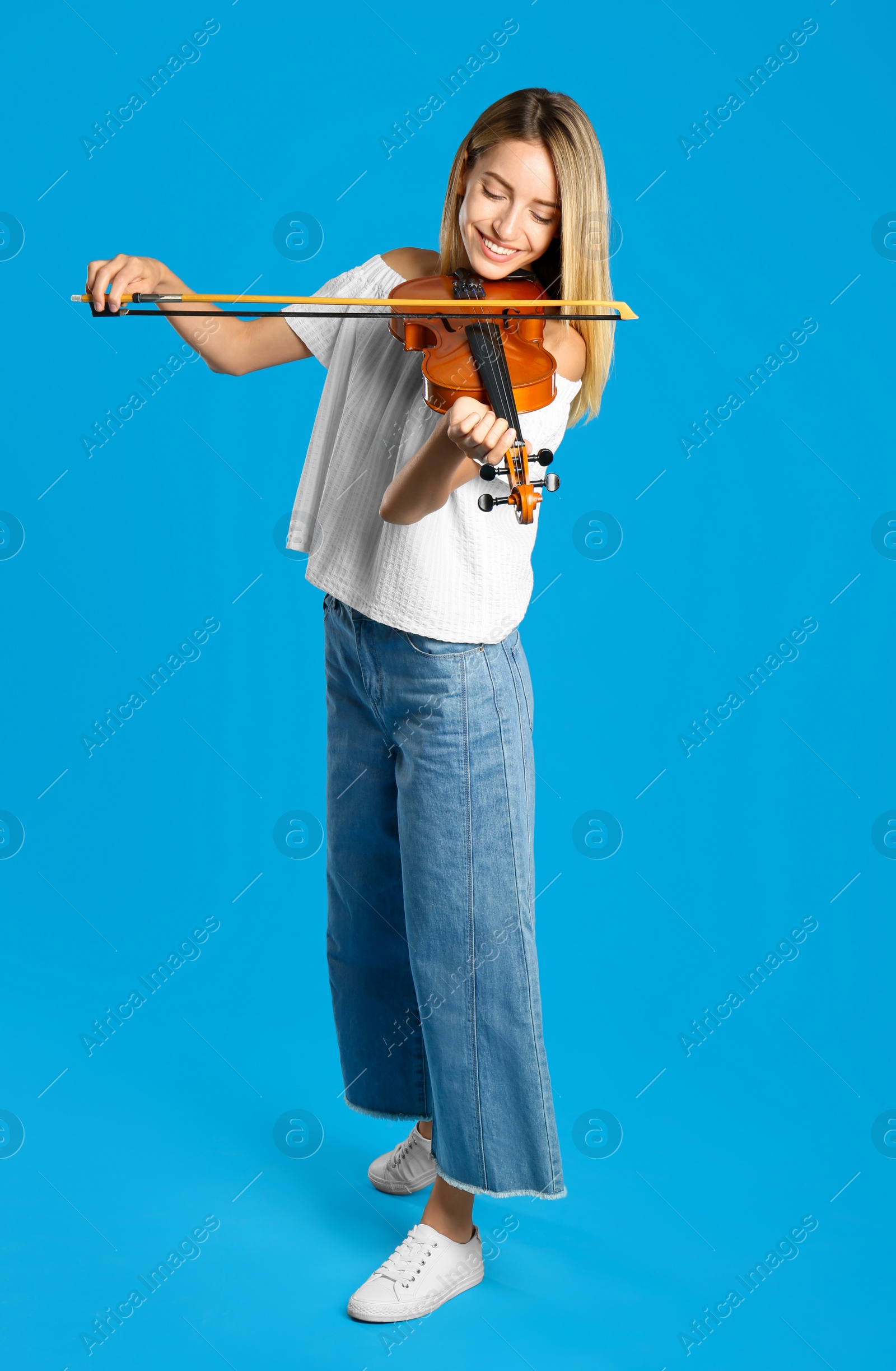 Photo of Beautiful woman playing violin on blue background