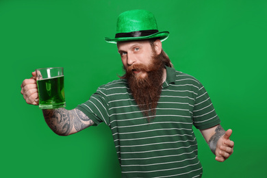 Photo of Bearded man with green beer on color background. St. Patrick's Day celebration