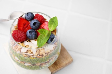 Tasty oatmeal with chia matcha pudding and berries on white table, closeup. Space for text. Healthy breakfast