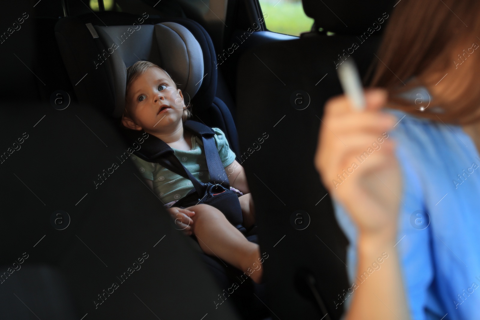 Photo of Mother with cigarette and child in car, closeup. Don't smoke near kids