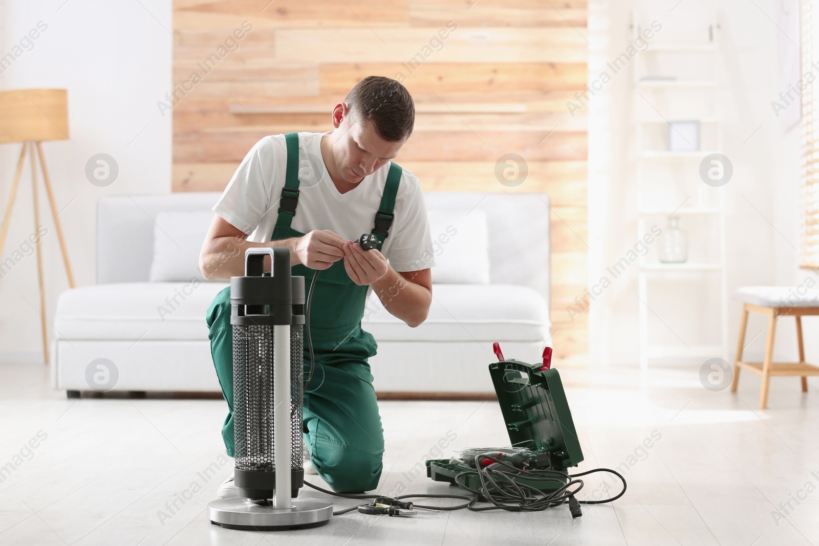 Photo of Professional technician repairing electric patio heater indoors