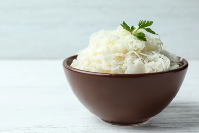 Photo of Tasty fermented cabbage on wooden table, closeup