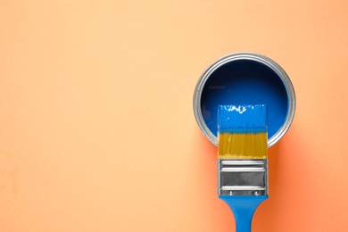 Can of paint and brush on orange background, top view with space for text. Color of the year 2020 (Classic blue)
