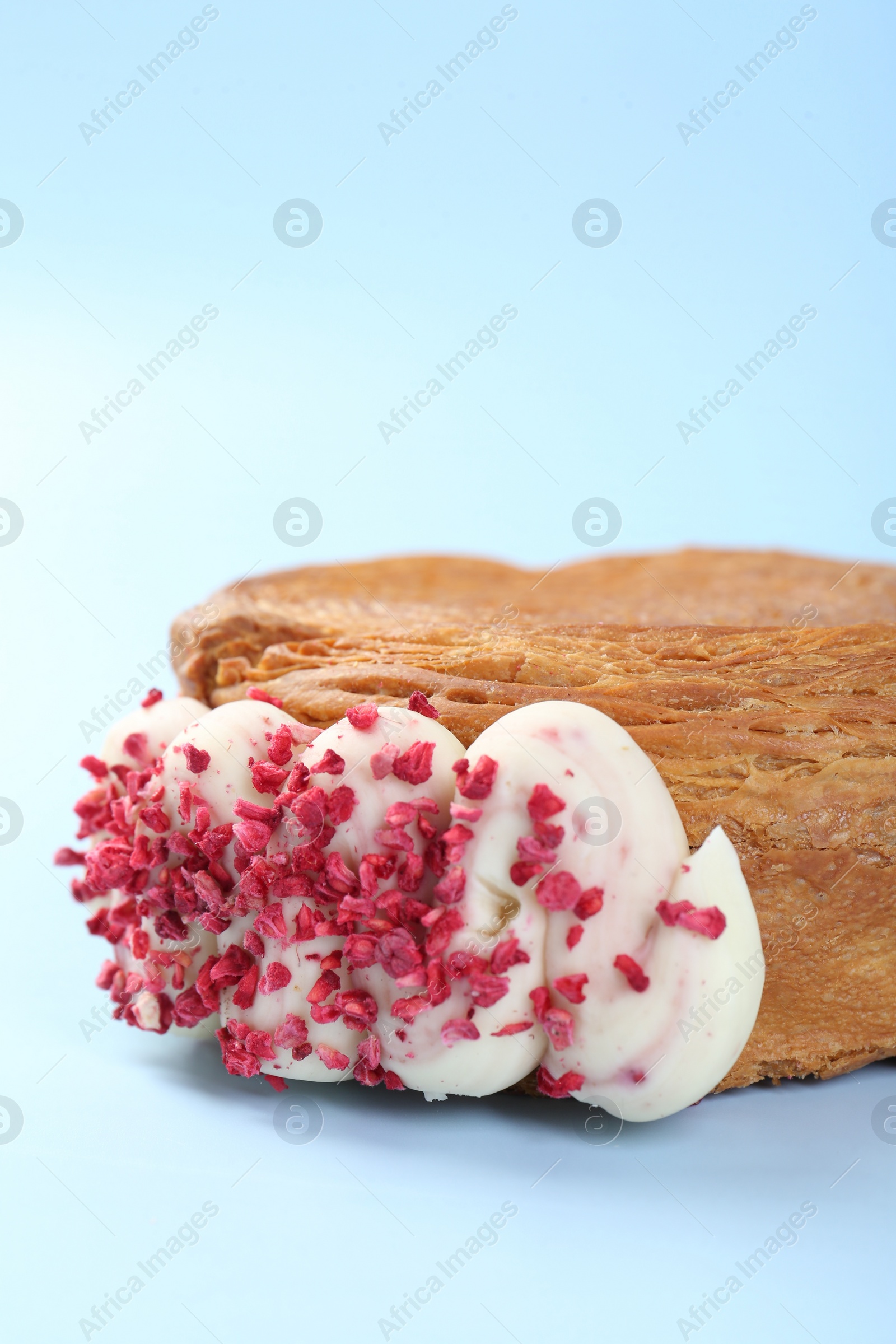 Photo of One supreme croissant with cream on light blue background, closeup. Tasty puff pastry