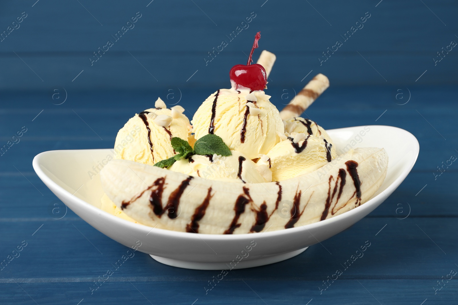 Photo of Delicious dessert with banana ice cream on blue wooden table