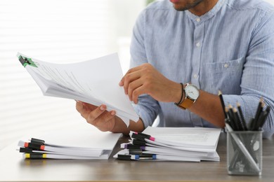 Man working with documents at wooden table in office, closeup