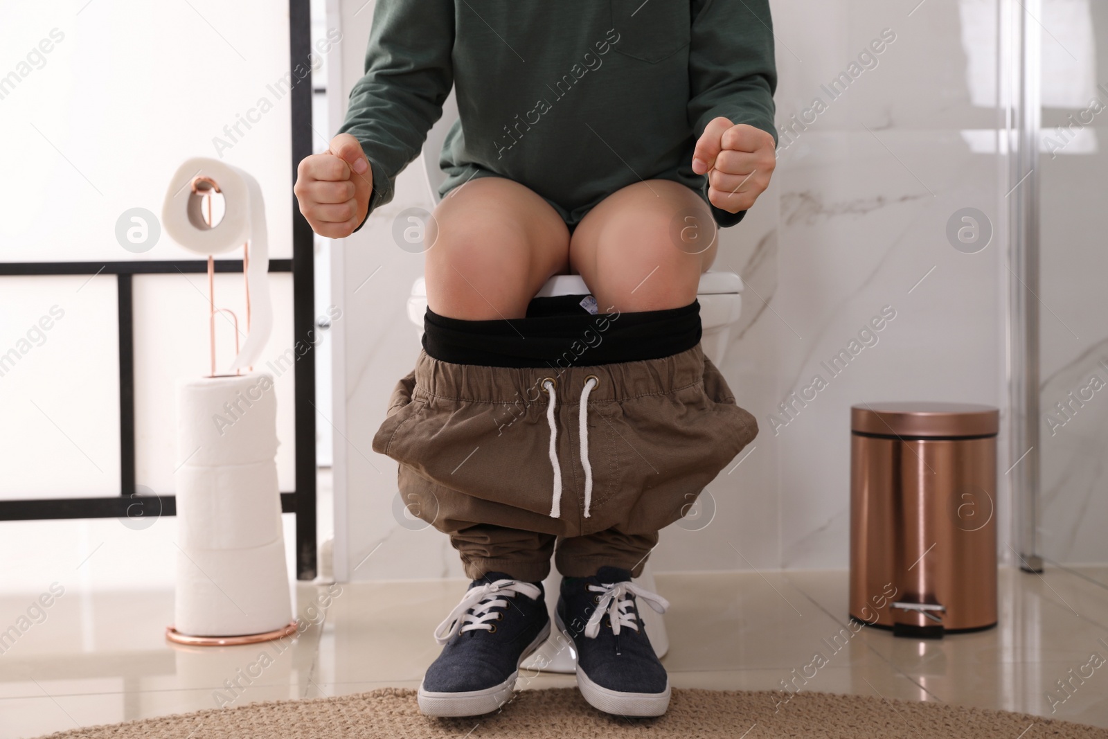 Photo of Boy suffering from hemorrhoid on toilet bowl in rest room, closeup