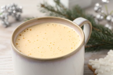 Photo of Cup of delicious eggnog on table, closeup