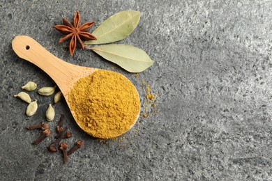 Photo of Spoon with dry curry powder and other spices on dark textured table, flat lay. Space for text