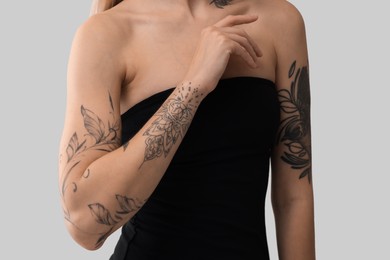 Woman with cool tattoos on light background, closeup