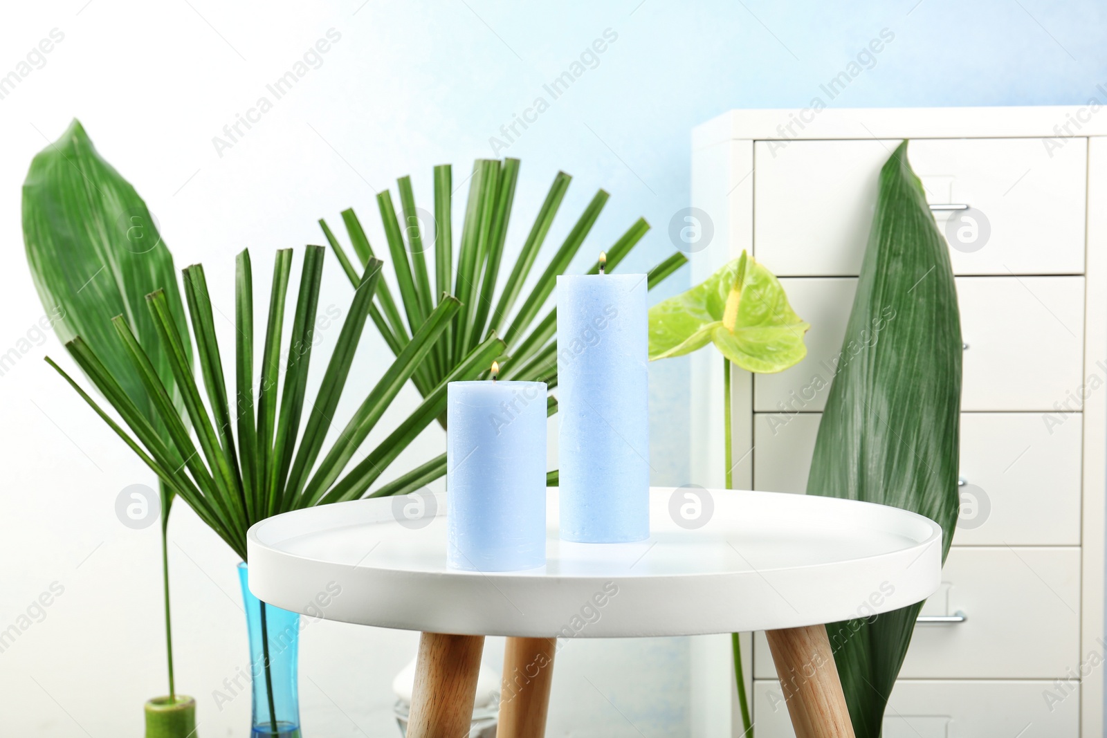 Photo of Creative composition with candles and tropical plants indoors