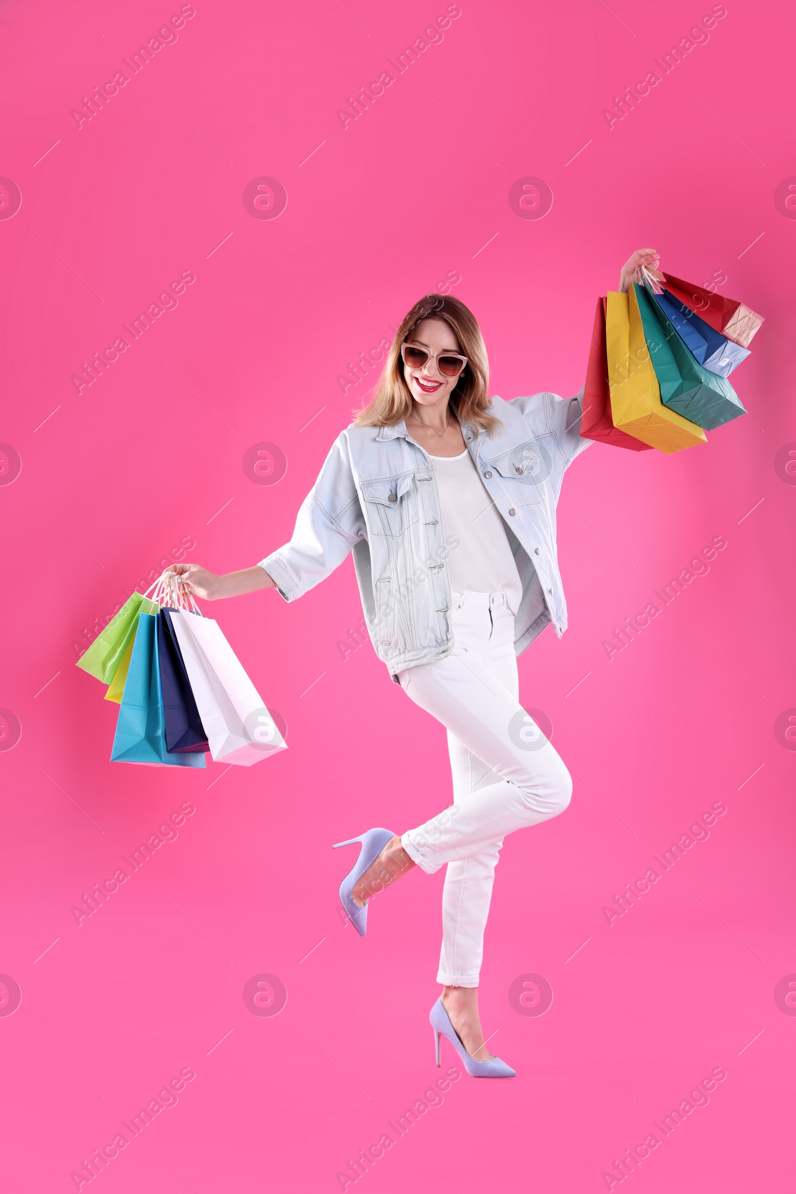 Photo of Beautiful young woman with shopping bags on color background