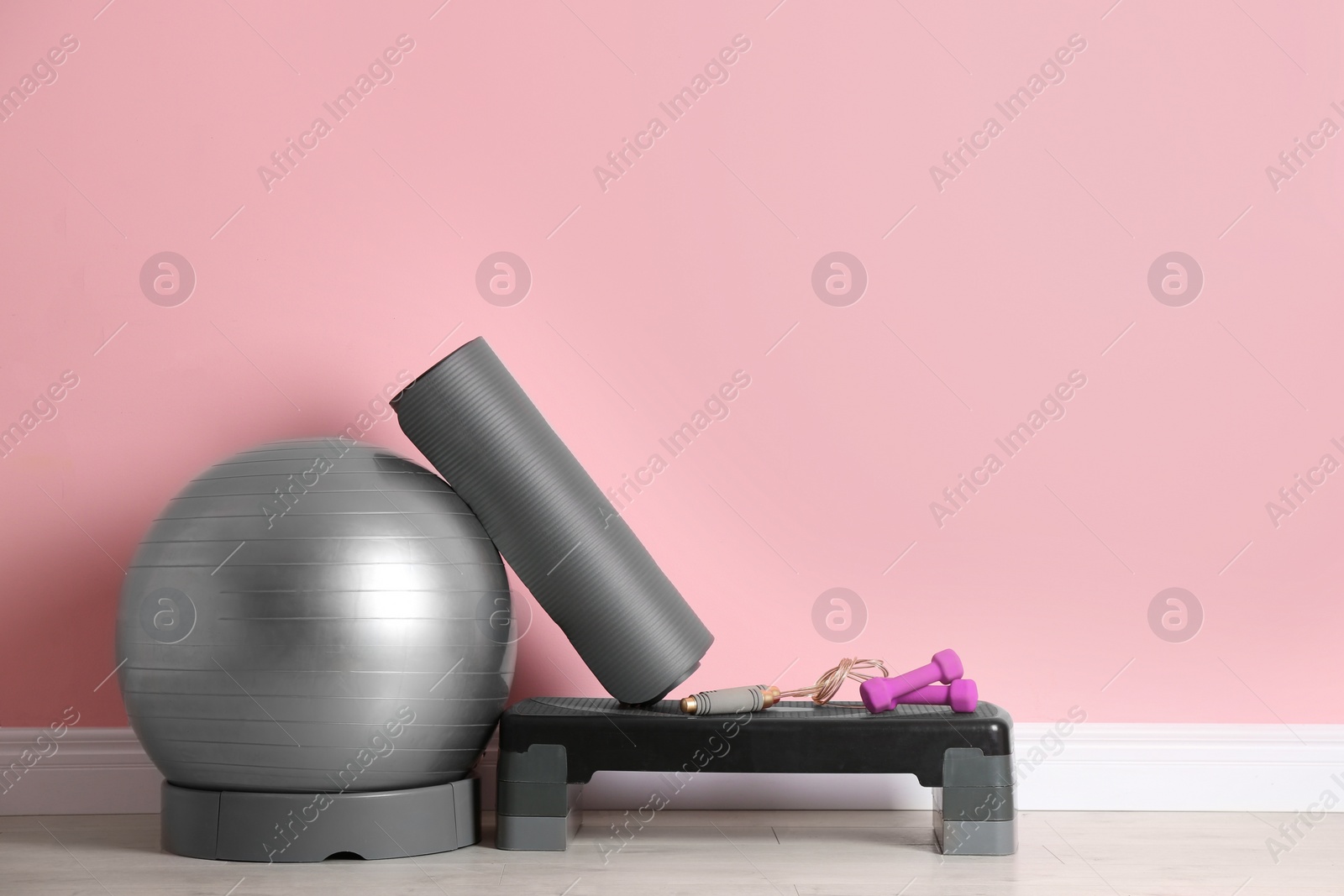 Photo of Set of fitness inventory on floor near color wall. Space for text