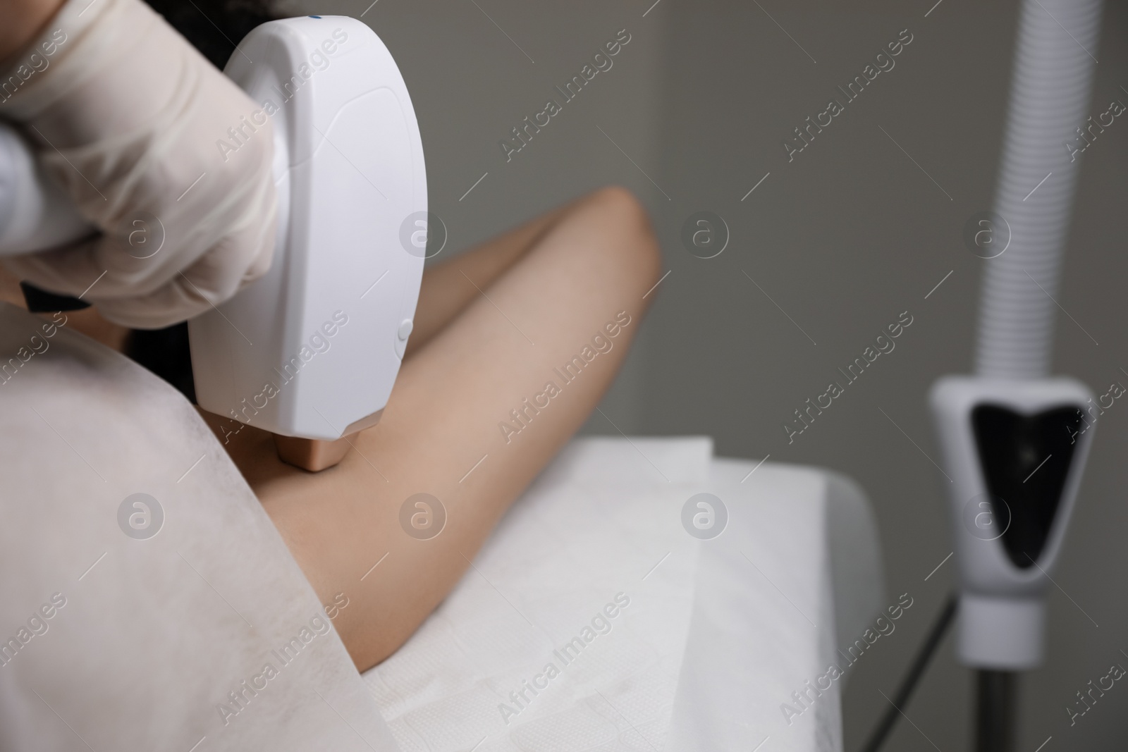 Photo of Woman undergoing laser epilation procedure in beauty salon, closeup