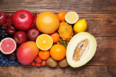 Many different fresh fruits and berries on wooden table, flat lay