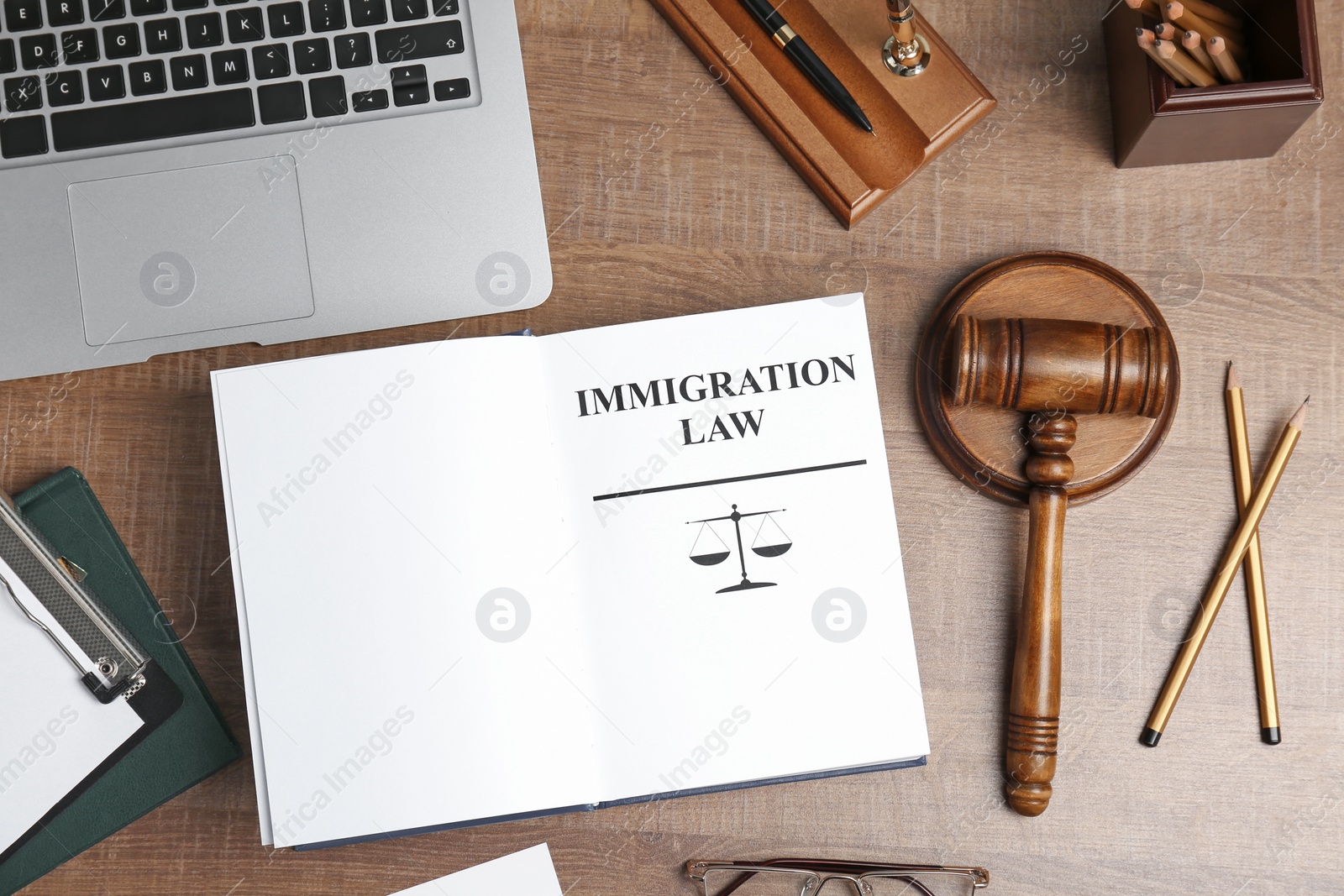 Photo of Flat lay composition with book, gavel and laptop on wooden background. Immigration law concept