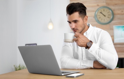 Portrait of handsome young man with laptop in office