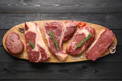 Pieces of raw beef meat and spices on black wooden table, top view