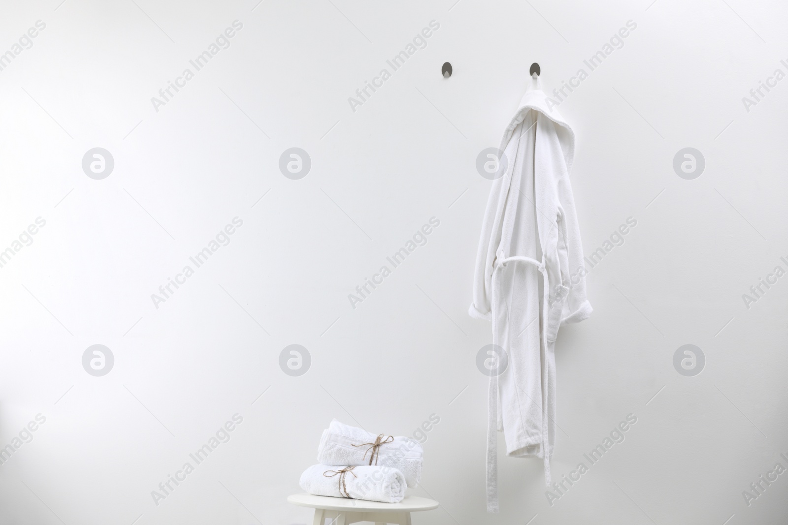 Photo of Soft comfortable bathrobe and towels indoors, space for text