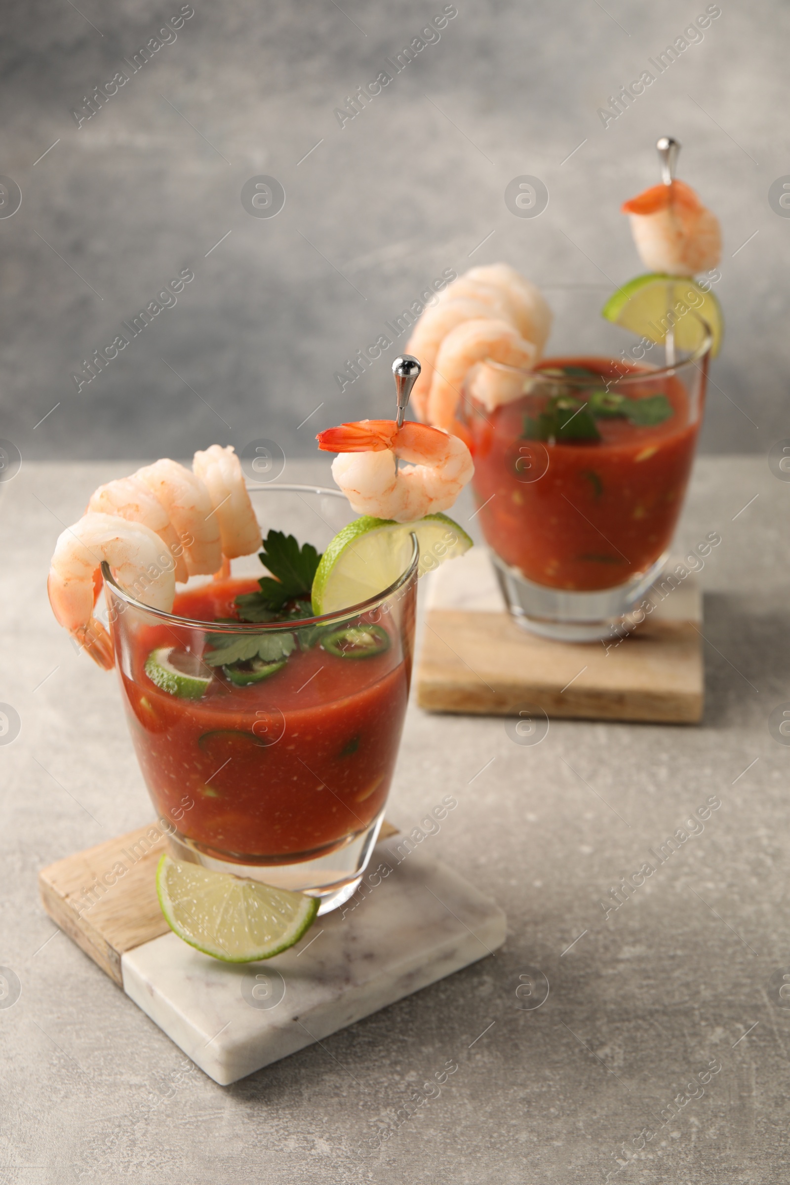 Photo of Tasty shrimp cocktail with sauce in glasses and lime on light grey table