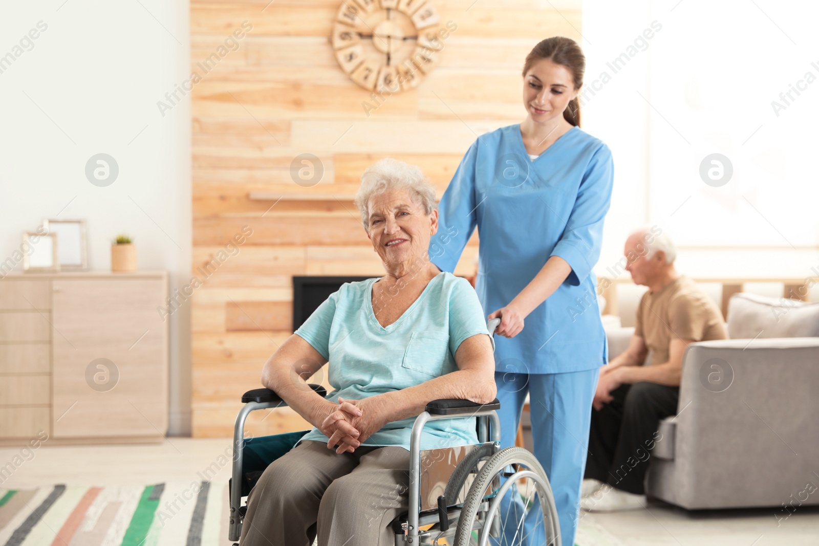 Photo of Nurse assisting elderly woman in wheelchair at retirement home. Space for text