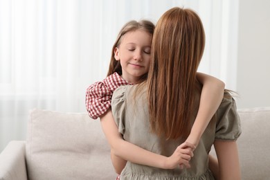 Cute daughter hugging her mom at home. Space for text