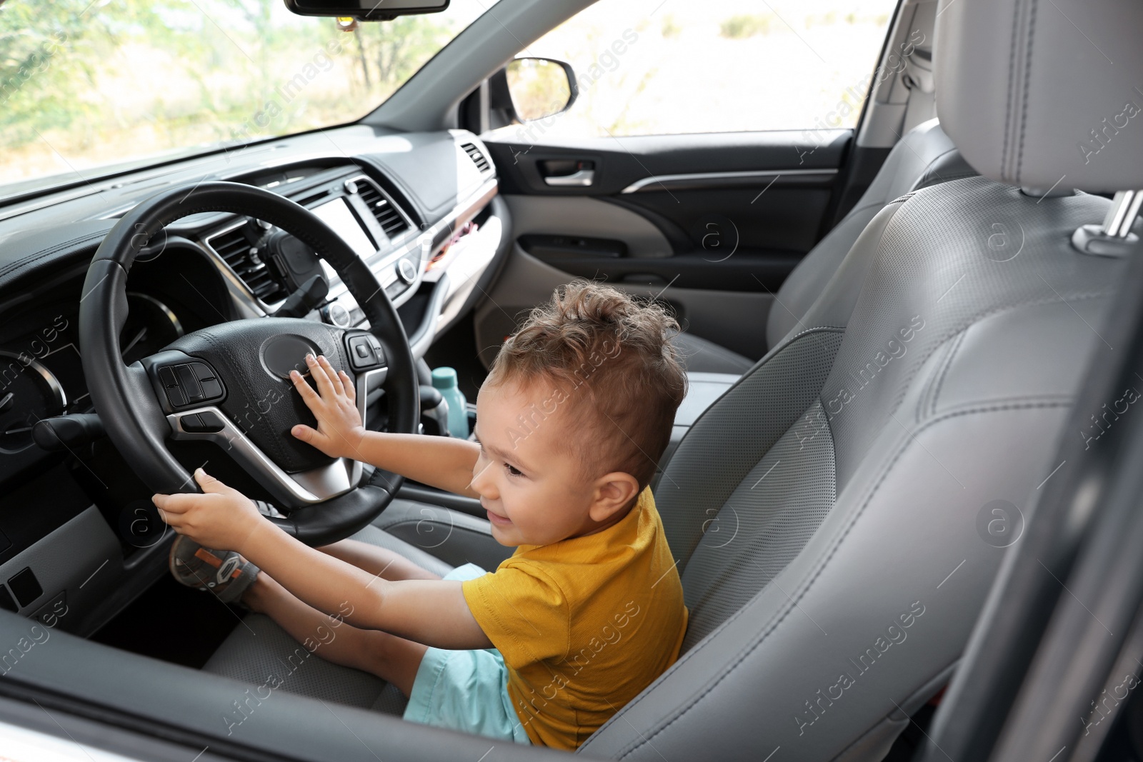 Photo of Little boy playing with steering wheel in car. Family trip