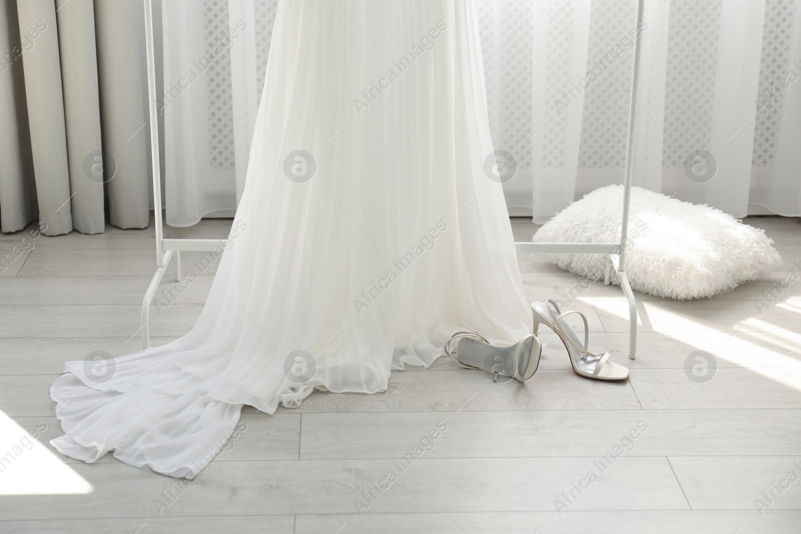 Photo of Beautiful wedding dress and shoes in room