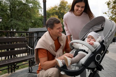 Photo of Happy parents walking with their adorable baby in stroller outdoors