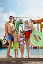 Happy family with inflatable ring near pool in water park