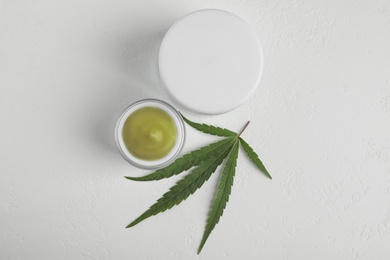 Jars of hemp cream on white table, flat lay. Organic cosmetics