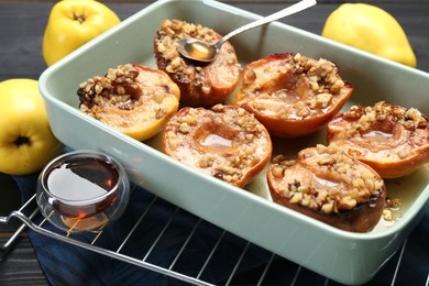 Tasty baked quinces with nuts and honey in dish on table, closeup