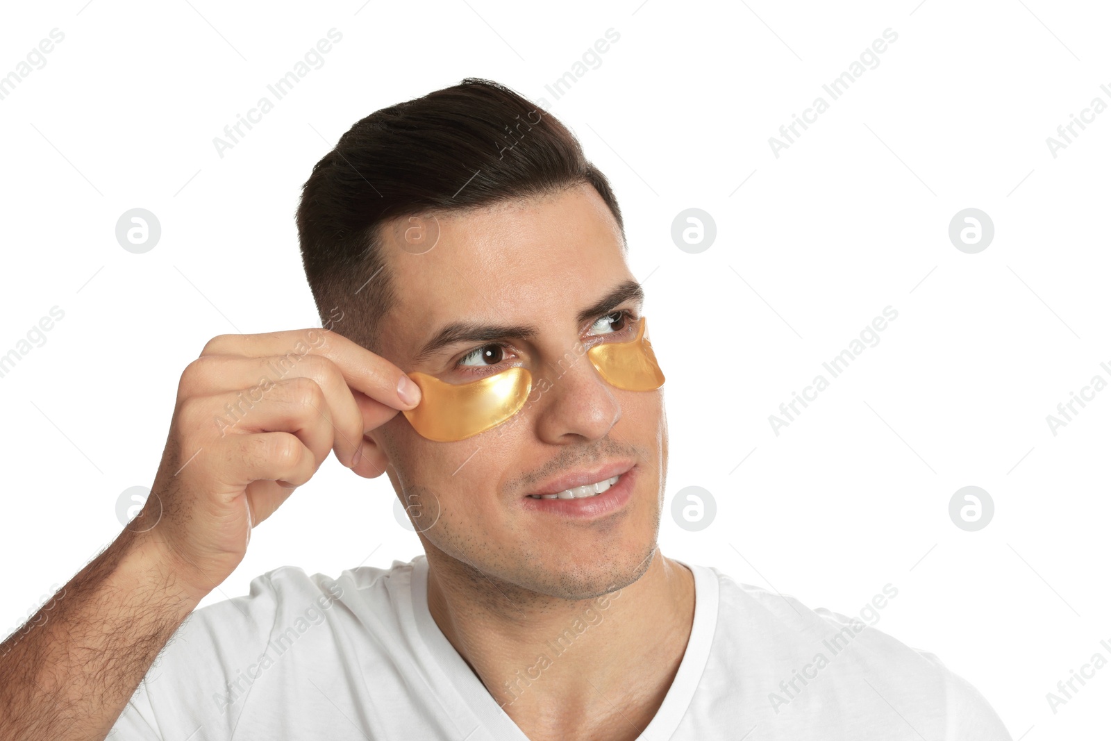 Photo of Man applying golden under eye patch on white background