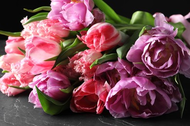 Photo of Beautiful bouquet of colorful tulip flowers on black table, closeup
