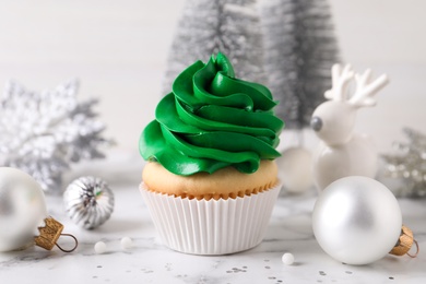 Photo of Delicious cupcake with green cream and Christmas decor on white marble table