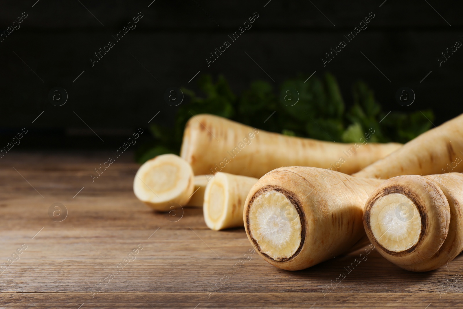 Photo of Fresh ripe parsnips on wooden table, closeup. Space for text