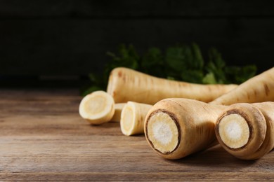 Photo of Fresh ripe parsnips on wooden table, closeup. Space for text